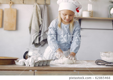 Little girl in a white shef hat cook the dough for cookies 62865468