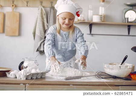 Little girl in a white shef hat cook the dough for cookies 62865471