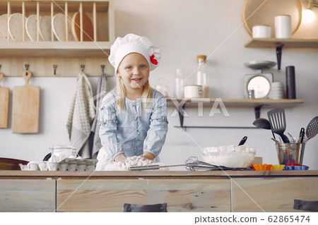 Little girl in a white shef hat cook the dough for cookies Little girl in a white shef hat cook the dough for cookies 62865474