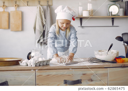 Little girl in a white shef hat cook the dough for cookies 62865475