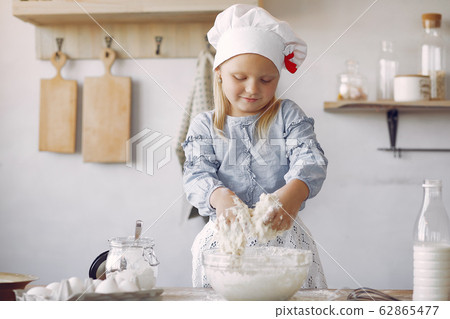 Little girl in a white shef hat cook the dough for cookies 62865477