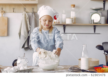 Little girl in a white shef hat cook the dough for cookies Little girl in a white shef hat cook the dough for cookies 62865478