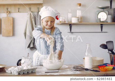 Little girl in a white shef hat cook the dough for cookies 62865481