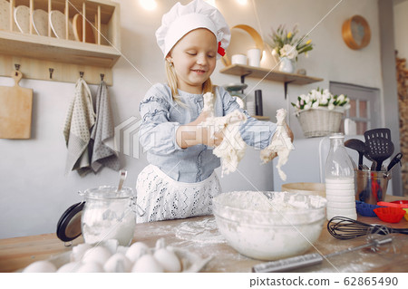 Little girl in a white shef hat cook the dough for cookies Little girl in a white shef hat cook the dough for cookies 62865490