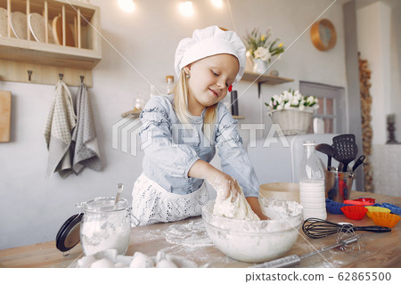 Little girl in a white shef hat cook the dough for cookies Little girl in a white shef hat cook the dough for cookies 62865500