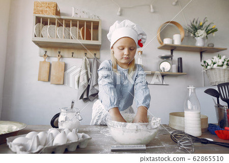 Little girl in a white shef hat cook the dough for cookies Little girl in a white shef hat cook the dough for cookies 62865510