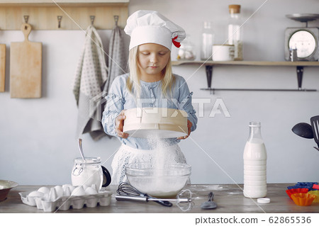 Little girl in a white shef hat cook the dough for cookies Little girl in a white shef hat cook the dough for cookies 62865536