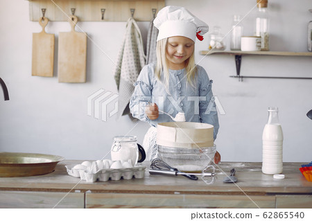 Little girl in a white shef hat cook the dough for cookies Little girl in a white shef hat cook the dough for cookies 62865540