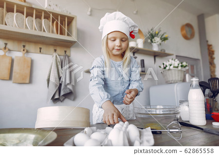 Little girl in a white shef hat cook the dough for cookies Little girl in a white shef hat cook the dough for cookies 62865558