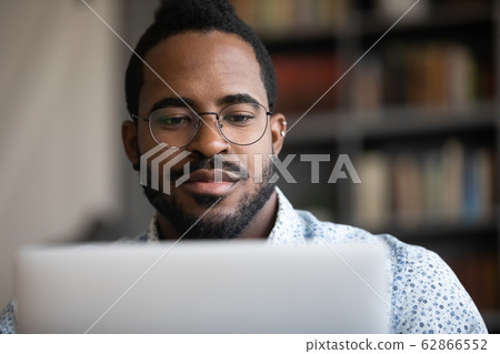 Close up focused young african ethnicity man working on computer. 62866552