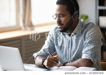 Focused young african american man watching educational lecture online. 62866569