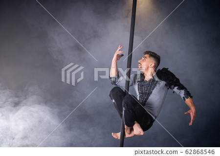 Performance concept. Man hanging on chinese pole. Athlete performing flying pole Performance concept. Man hanging on chinese pole. Athlete performing flying pole 62868546