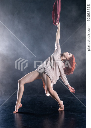 Female athletic, sexy and flexible aerial circus artist with redhead dancing in the air on the silk Female athletic, sexy and flexible aerial circus artist with redhead dancing in the air on the silk 62868818