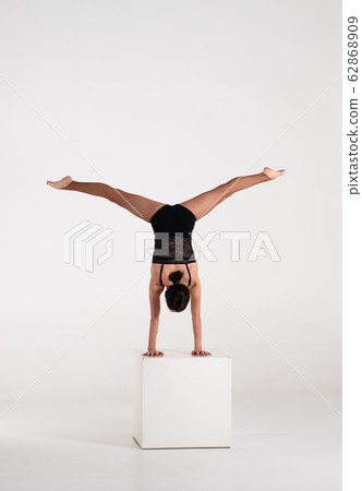 Good shaped man woman practicing handstand on white cube isolated on white background. Strength and 62868909