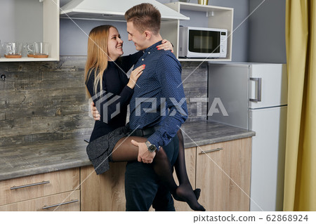 Young Caucasian spouses cuddling in the kitchen. 62868924