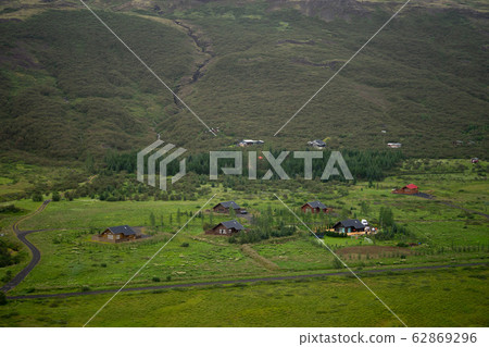 The farm is on a hill in the middle of a green field in rural Iceland. 62869296