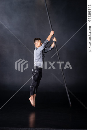 Performance concept. Man hanging on chinese pole. Athlete performing flying pole 62869541