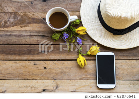 mobile phone ,hot coffee, purple flowers, yellow flowers ylang ylang and hat of lifestyle woman 62876641