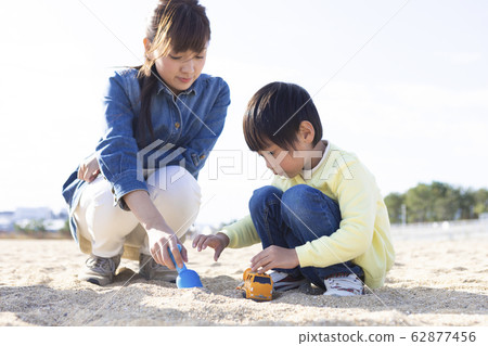 Parent and child playing on the sandy beach 62877456
