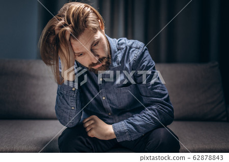 Mature man sitting on couch and feeling depressed 62878843