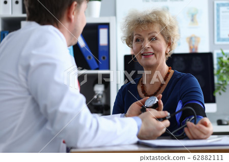 Male doctor measures pressure an elderly woman Male doctor measures pressure an elderly woman 62882111
