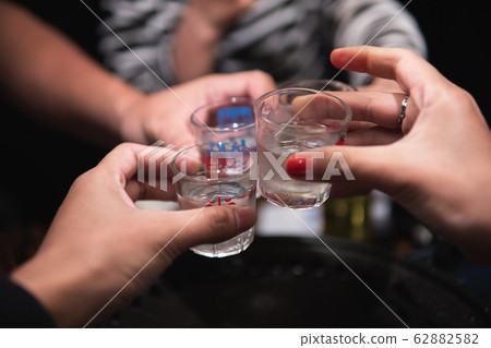 Old friends cheers with Soju in the Yakiniku Old friends cheers with Soju in the Yakiniku 62882582