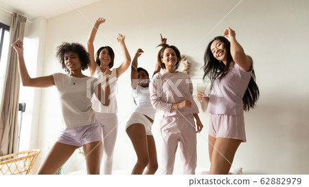 Portrait beautiful diverse girls dancing on bed together 62882979