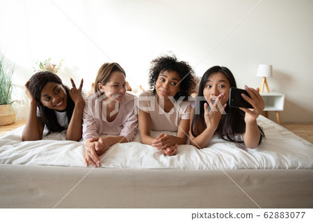 Beautiful Asian woman taking selfie with friends at sleepover party Beautiful Asian woman taking selfie with friends at sleepover party 62883077