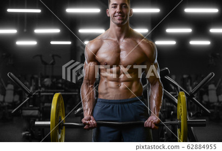 Bodybuilder strong man pumping up biceps muscles 62884955