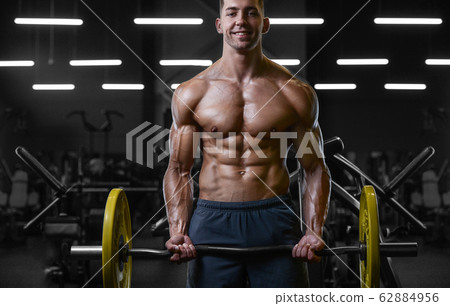 Bodybuilder strong man pumping up biceps muscles Bodybuilder strong man pumping up biceps muscles 62884956