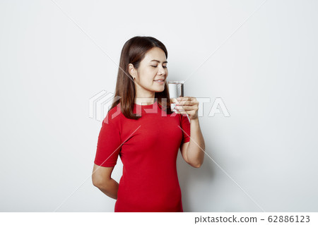 Young beautiful woman drinks water from a glass Young beautiful woman drinks water from a glass 62886123