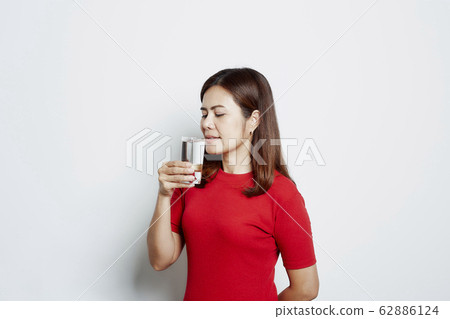 Young beautiful woman drinks water from a glass Young beautiful woman drinks water from a glass 62886124