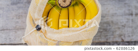 Banana in a reusable bag on a stylish wooden kitchen surface. Zero waste concept, plastic free Banana in a reusable bag on a stylish wooden kitchen surface. Zero waste concept, plastic free 62886126