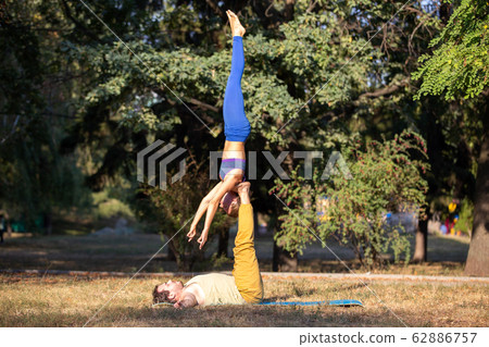 Acro yoga couple practising shoulder stand pose 62886757
