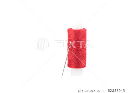 Close-up photo of a spool with red thread and a needle isolated over white background. Close-up photo of a spool with red thread and a needle isolated over white background. 62888943