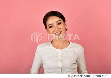Beautiful asian woman relaxing on pink background. 62889652