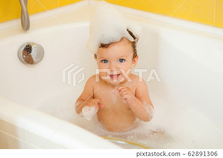 Smiling kid with foam and soap bubbles in bathroom. 62891306