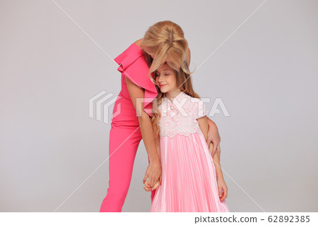 Mom with her daughter in white dresses in the studio. 62892385