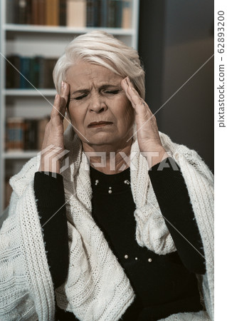 Expressive Elderly Blonde Feels A Headache From Stress 62893200