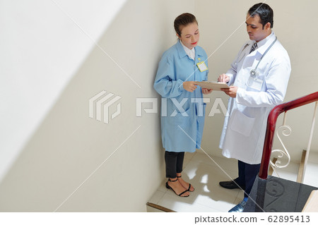 Indian doctor showing document to colleague 62895413