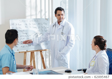 General practitioner showing surgery timetable General practitioner showing surgery timetable 62895467