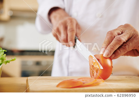 Man cutting tomato Man cutting tomato 62896950