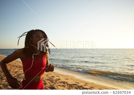 Happy woman running on beach Happy woman running on beach 62897034