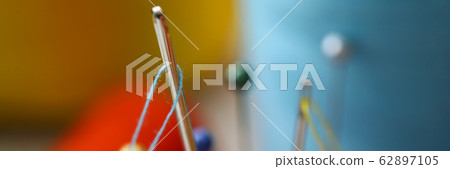 Needle eye with piece of blue thread stick out of pincushion Needle eye with piece of blue thread stick out of pincushion 62897105