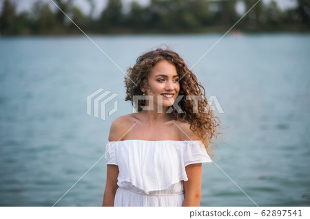 Front view of young woman at summer festival, standing in lake. 62897541
