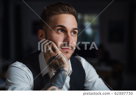 A front view of young businessman indoors in office, working late. 62897730
