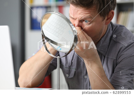 Man sits in front mirror and presses on his face Man sits in front mirror and presses on his face 62899553