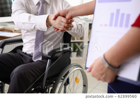 Man in suit sits in wheelchair and shakes his hand 62899560
