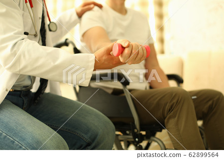 Handicapped man sits working out dumbbell arm Handicapped man sits working out dumbbell arm 62899564