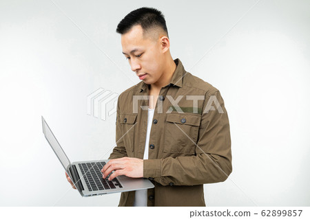 Asian man typing on a laptop keyboard on a white studio background 62899857